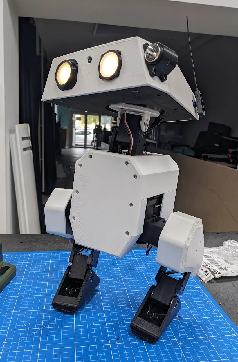 Assembled Open Duck Mini v2 robot standing on a blue workshop cutting mat